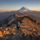 Hiker walking carefully on a rocky Atlas Mountain trail toward Mount Toubkal at sunrise