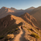Hiker on a high Atlas Mountain trail beneath rugged Mount Toubkal peaks at golden morning light